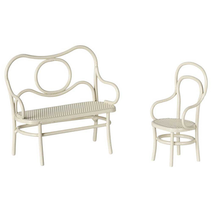 Das Café-Set von Maileg umfasst eine cremefarbene Bank im Vintage-Stil mit runder Rückenlehne und einen dazu passenden Stuhl mit einer kunstvoll geschwungenen Rückenlehne, beide mit Korbsitzfläche.