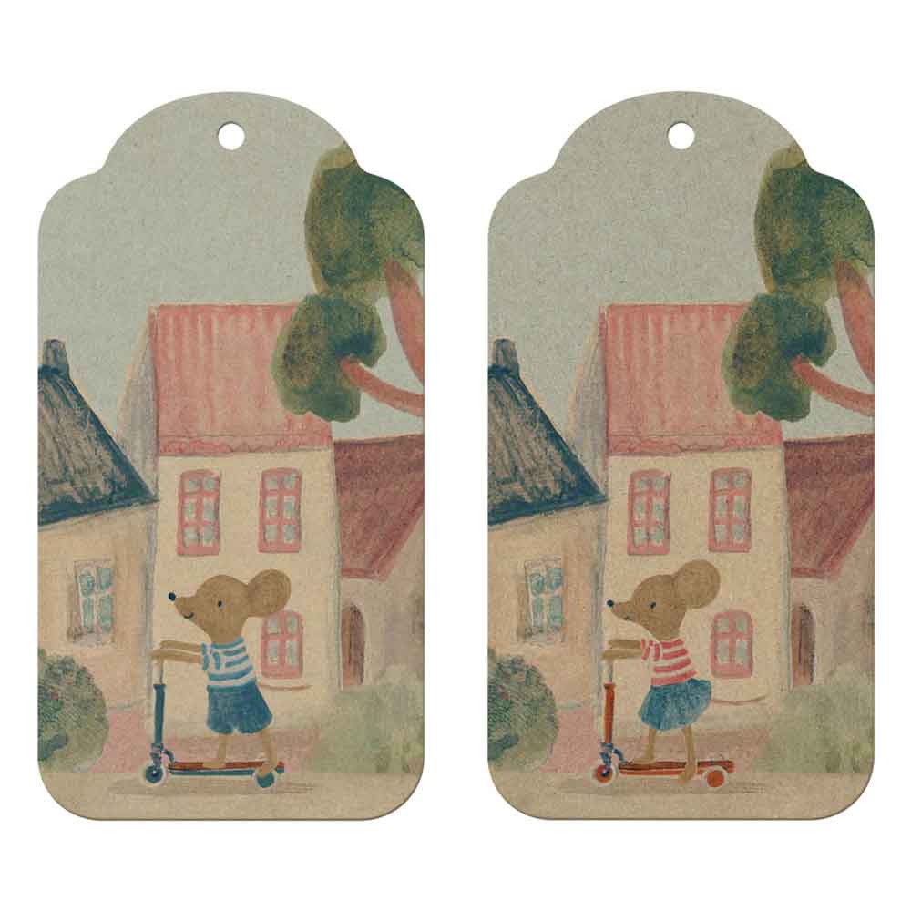 Der Maileg - Geschenkanhänger Maus 12 Stück zeigt eine Illustration einer Maus auf einem Roller vor Häusern, gedruckt auf zwei identischen, runden Anhängern mit Löchern zum Aufhängen.