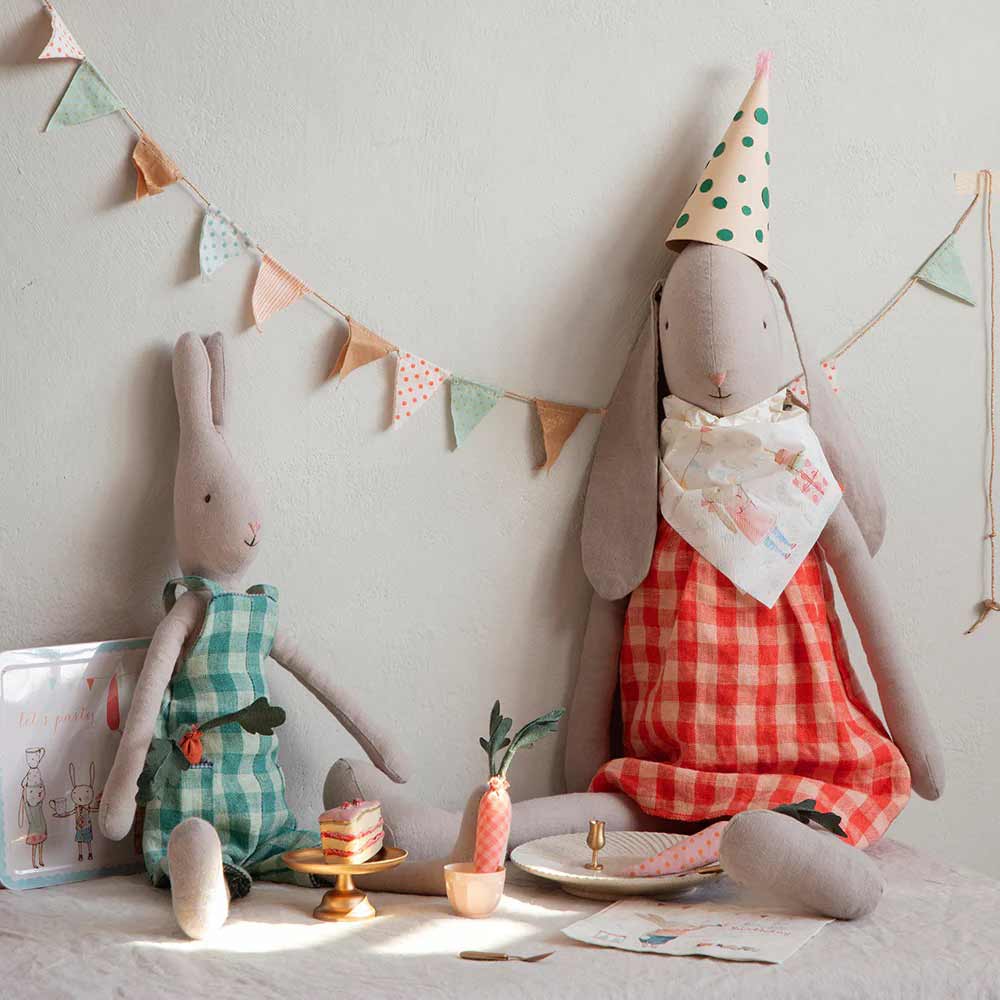 Zwei Maileg Hase Bunny-Puppen in karierten Kleidern (Größe 5, Höhe: 64 cm) sind für eine Teeparty eingerichtet, mit einem kleinen Kuchen, einer dekorierten Wand und einem Hasen mit Partyhut.