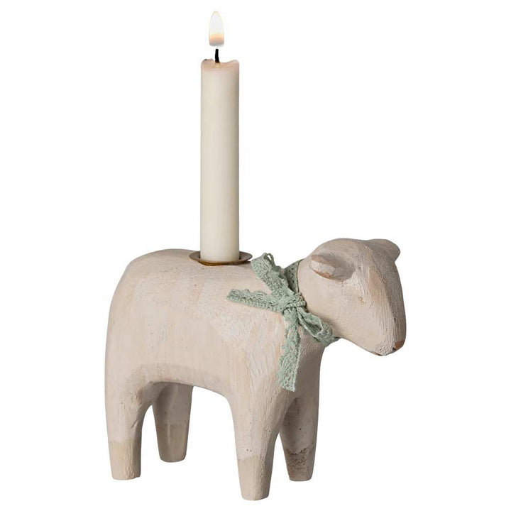 Der Maileg - Kerzenhalter Lamm ist ein hölzerner Kerzenhalter in Schafform mit einer brennenden weißen Kerze auf seinem Rücken und einer grünen Schleife um den Hals.