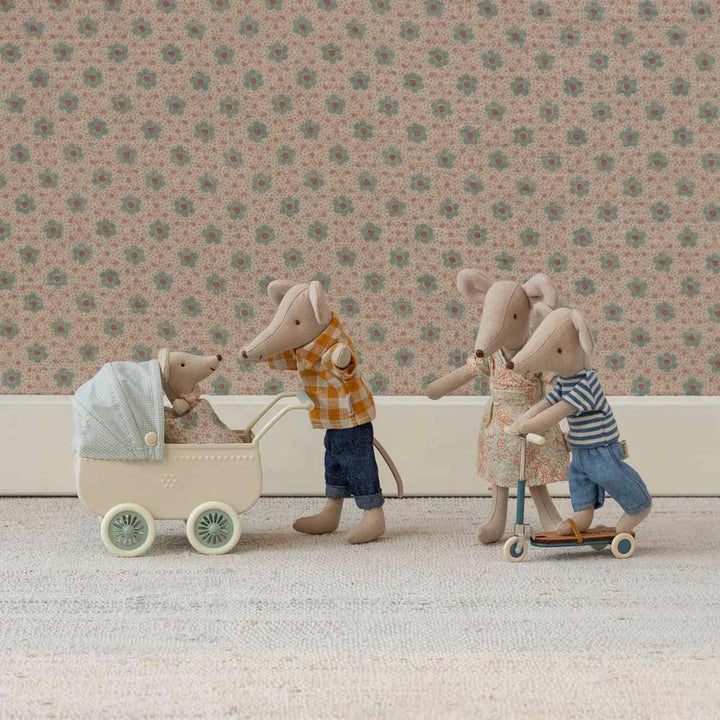 Ein Maileg Mama Maus-Set enthält vier Spielzeugmäuse: eine im Kinderwagen, zwei erwachsene Mäuse und eine auf einem Roller, alle vor einer geblümten Tapete.