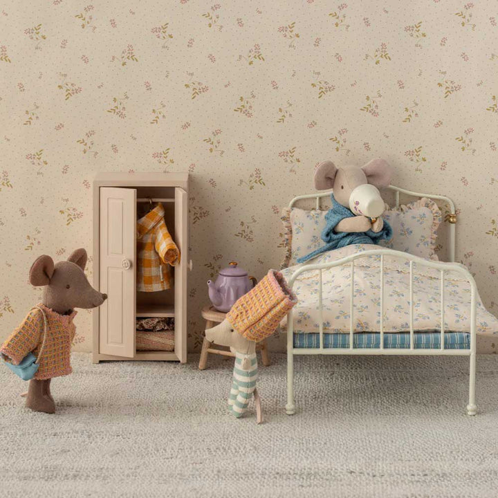 In einer Schlafzimmerszene sind Maileg-Mäuse vom Typ „Maus Anzug Mama“ abgebildet: Eine trinkt Tee im Bett, eine andere öffnet einen Kleiderschrank voller Kleidung und eine dritte trägt einen Pyjama und hält ein Kissen. Die Szenerie ist mit floralen Tapeten und Teppichen gestaltet.