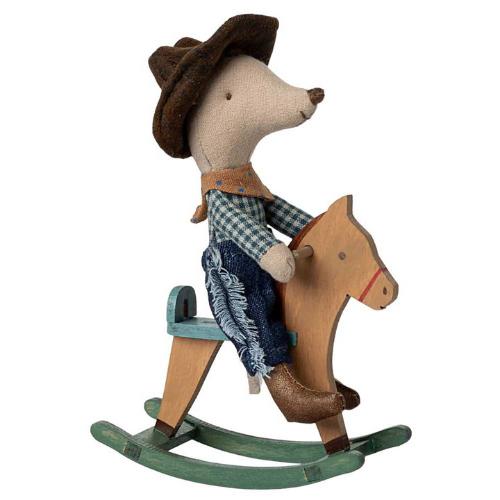 Die Maileg - Maus Cowboy auf Schaukelpferd Little Brother zeigt eine kleine Maus, die als Cowboy verkleidet ist, komplett mit Hut und Stiefeln, und auf einem hölzernen Schaukelpferd sitzt.