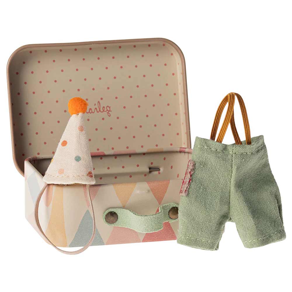 In einem kleinen offenen Koffer mit pastellfarbenem geometrischem Muster liegen eine gestreifte Miniatur-Partymütze mit Bommel und daneben ein Paar grüne Shorts mit gelben Hosenträgern: die Maileg – Maus Little Brother Clownskleidung im Koffer.