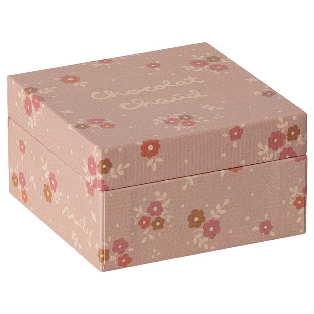 Eine rosafarbene, quadratische Geschenkbox, verziert mit Blumenmustern und dem Text „Chocolat Cheval“ auf dem Deckel, bekannt als Maileg – Miniatur Heiße Schokolade Set.