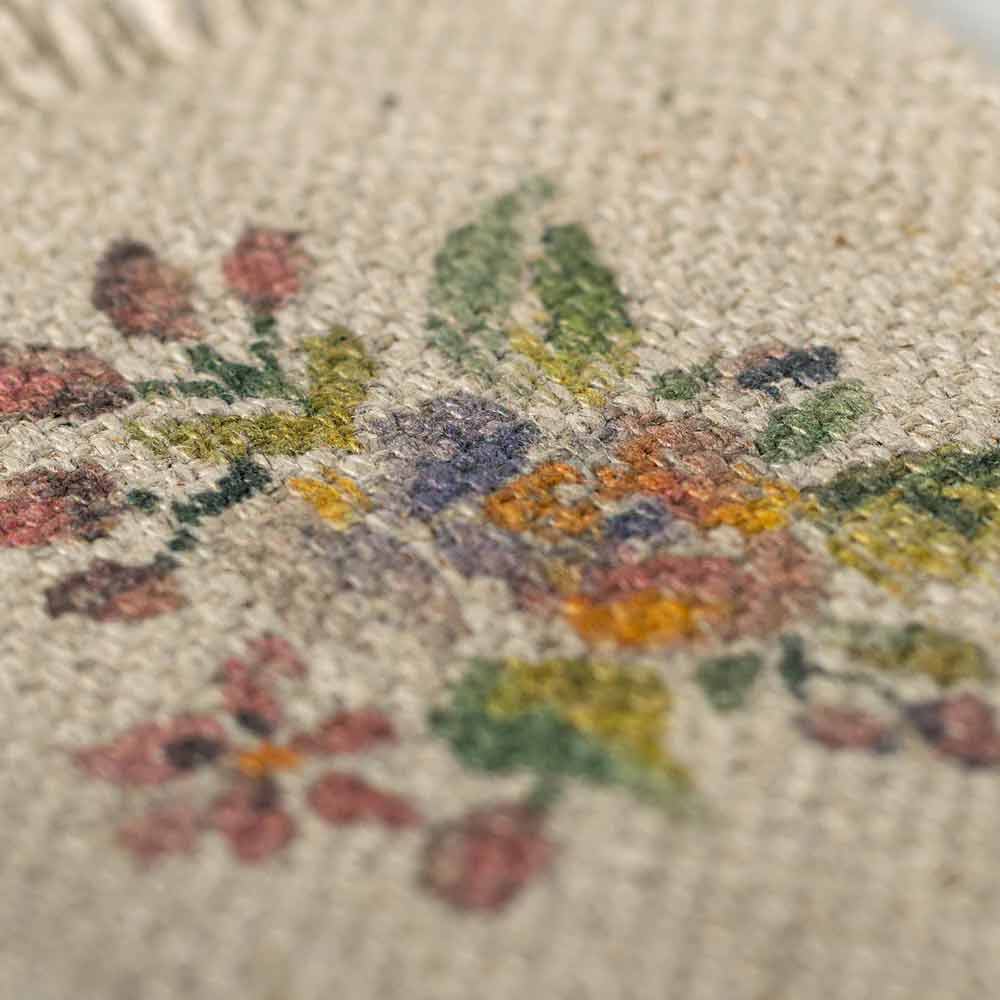 Nahaufnahme des Maileg-Miniatur-Teppichs Blumen, der eine Blumenstickerei in einer Reihe von Farben zeigt, darunter Grün, Rot und Gelb.