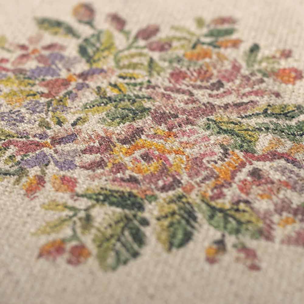 Nahaufnahme des Maileg-Miniatur-Teppichs Blumen, der sein florales Kreuzstichmuster mit rosa, violetten und gelben Blumen, ergänzt durch grüne Blätter, zeigt.