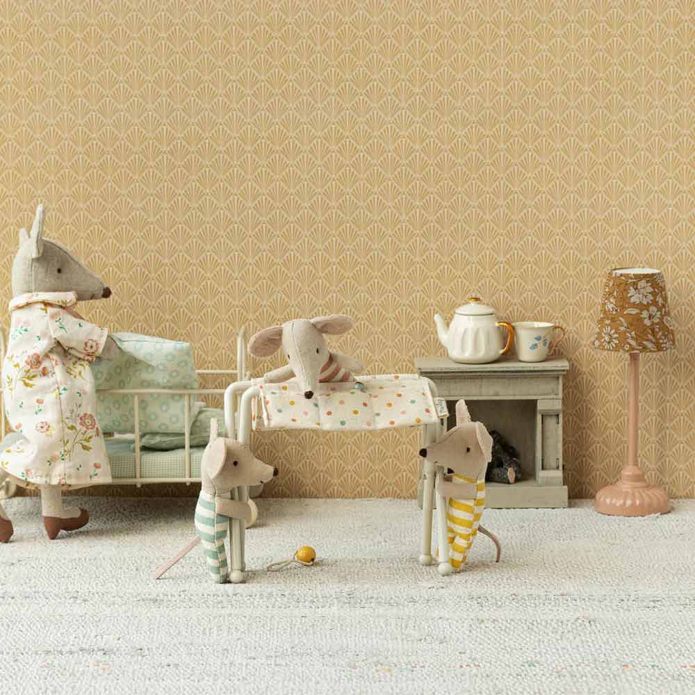 Eine bezaubernde Miniaturszene mit Plüschmäusen: Eine Maus im Bademantel steht neben einem Bett, eine andere gestreift gekleidete Maus kümmert sich um ein Kinderbett mit dem Wickeltisch „Maleg - Puppenmöbel Wickeltisch Maus“ in der Nähe und eine dritte gestreifte Maus hält einen Ball neben der Spielküche.