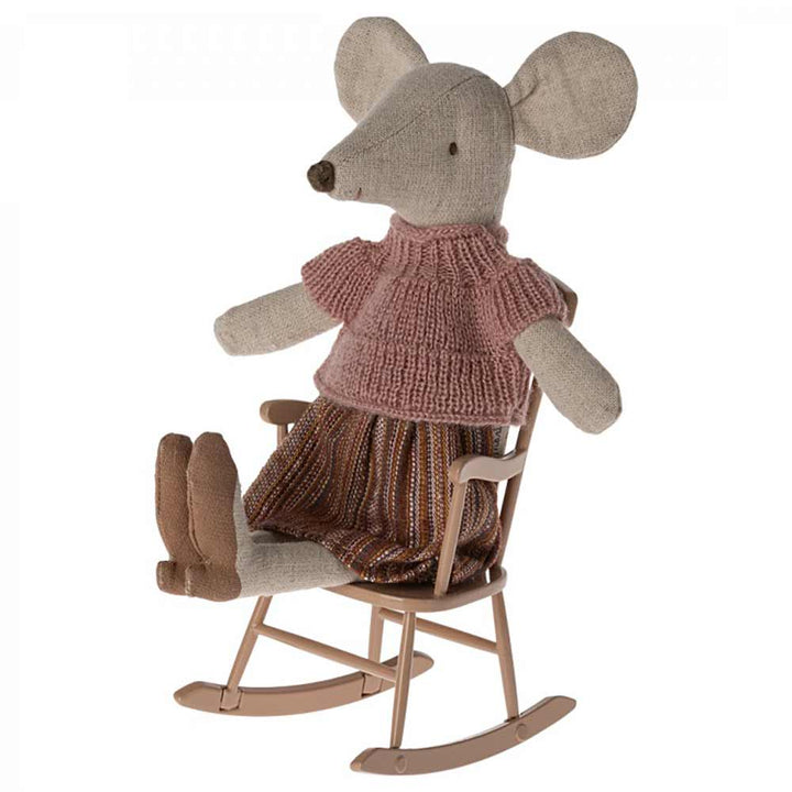 Eine Stoffmauspuppe mit einem rosa Strickpullover und einem gestreiften Rock sitzt auf einem Maileg-Schaukelstuhl Maus Altrosa.