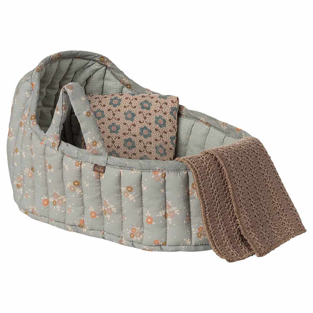 Die Maileg - Tragetasche Groß ist eine gepolsterte Stoffpuppentasche mit Blumenmuster, zwei Griffen, einem passenden Kissen und einer braunen Häkeldecke, die an der Seite drapiert ist.