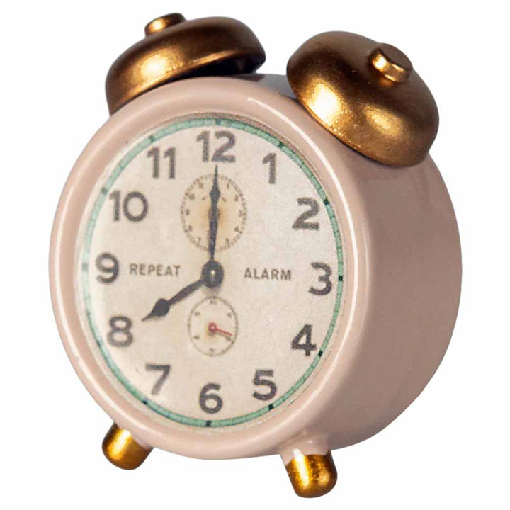 Der Maileg - Wecker Miniatur für Maus ist ein kleiner Wecker im Vintage-Stil mit goldenen Glöckchen und Standbeinen, einem weißen Zifferblatt mit den Zahlen 1-12 und zwei Zeigern bei 10:10.