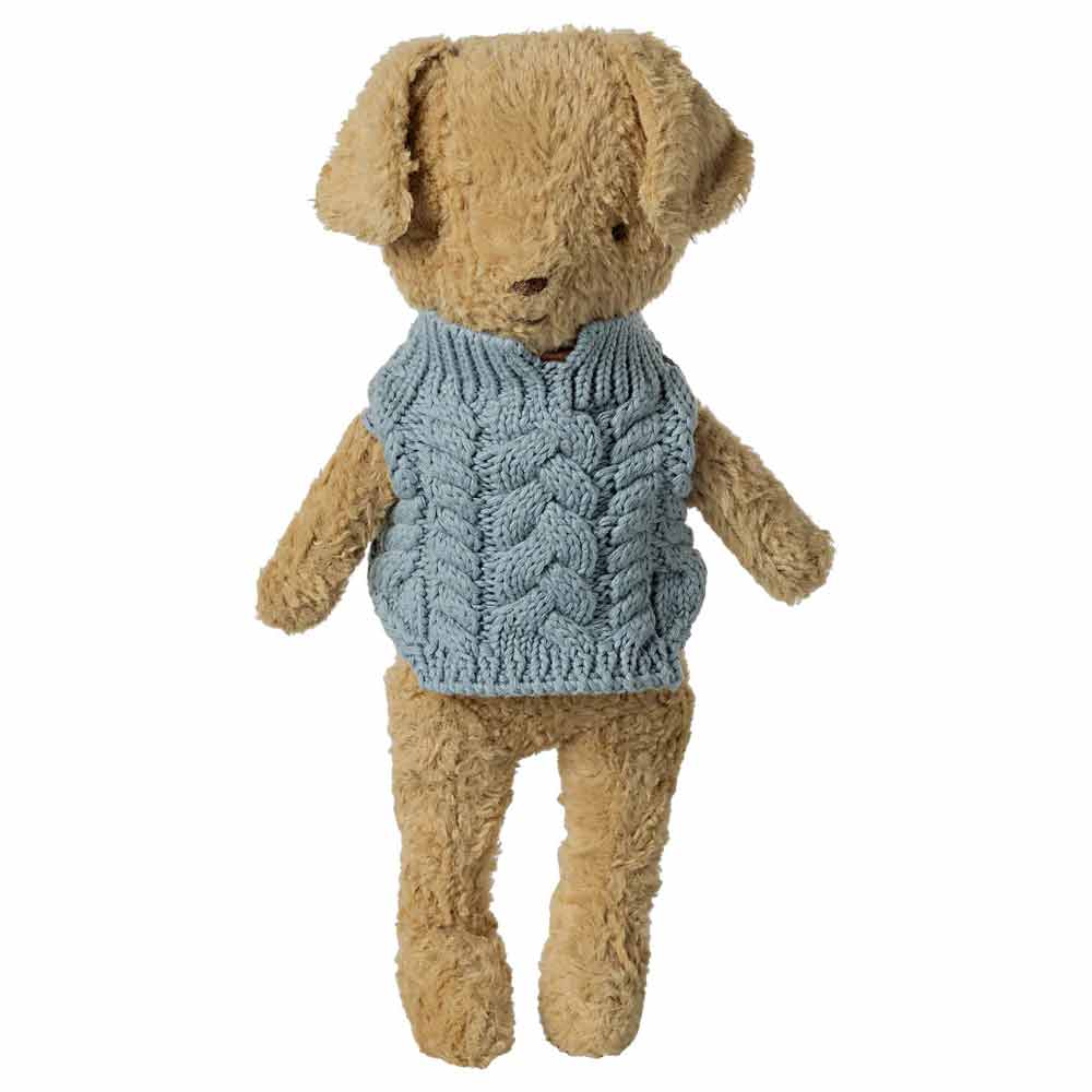 Ein Maileg-Teddybär trägt einen blauen Strickpullover und steht aufrecht vor einem schlichten weißen Hintergrund.