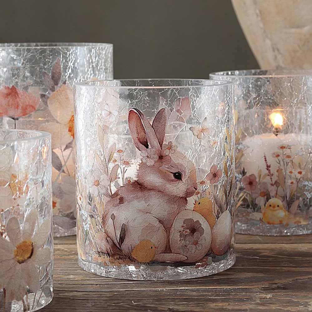 Das Majas Cottage - Windlicht Hase & Blumen ist ein Kerzenständer aus Glas, der mit floralen Mustern und Hasenillustrationen verziert ist. Wenn er angezündet wird, strahlt er ein warmes Licht aus.