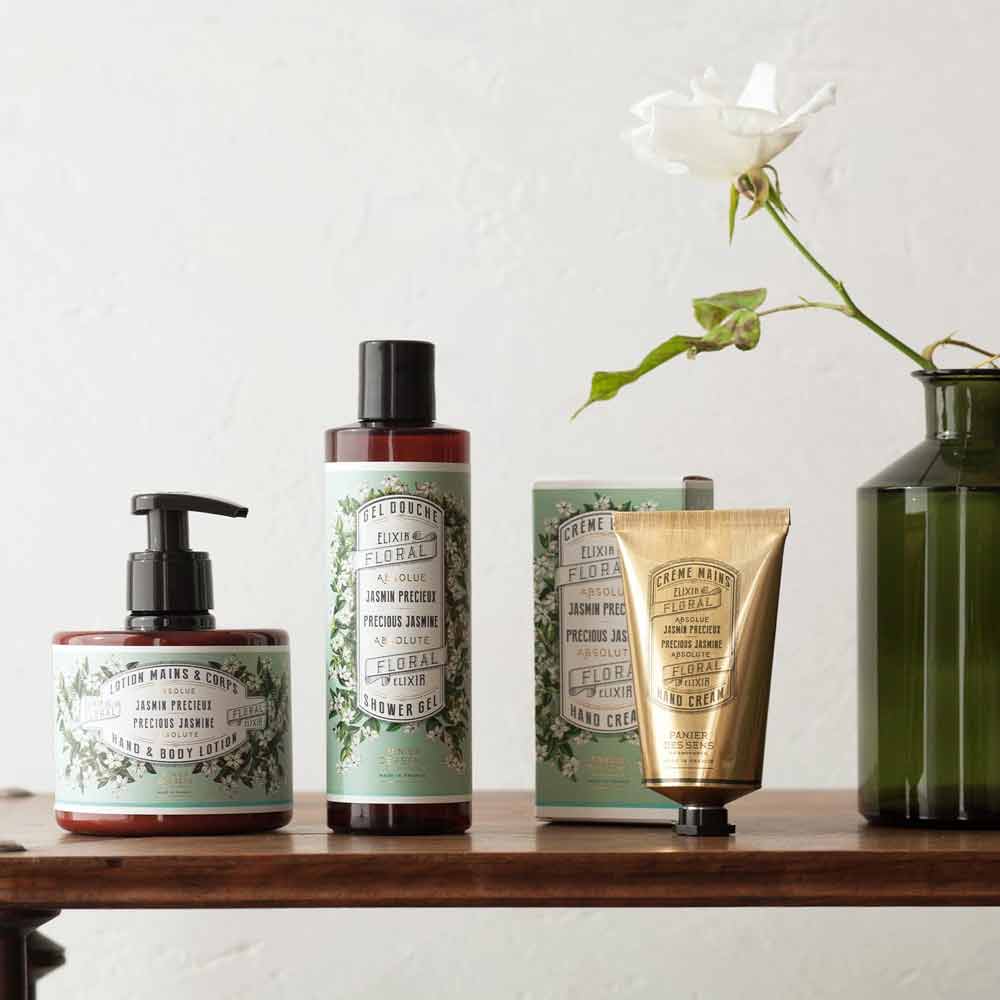 Eine Gruppe von Panier des Sens – Duschgel Jasmin 250ml und eine Vase mit Blumen.