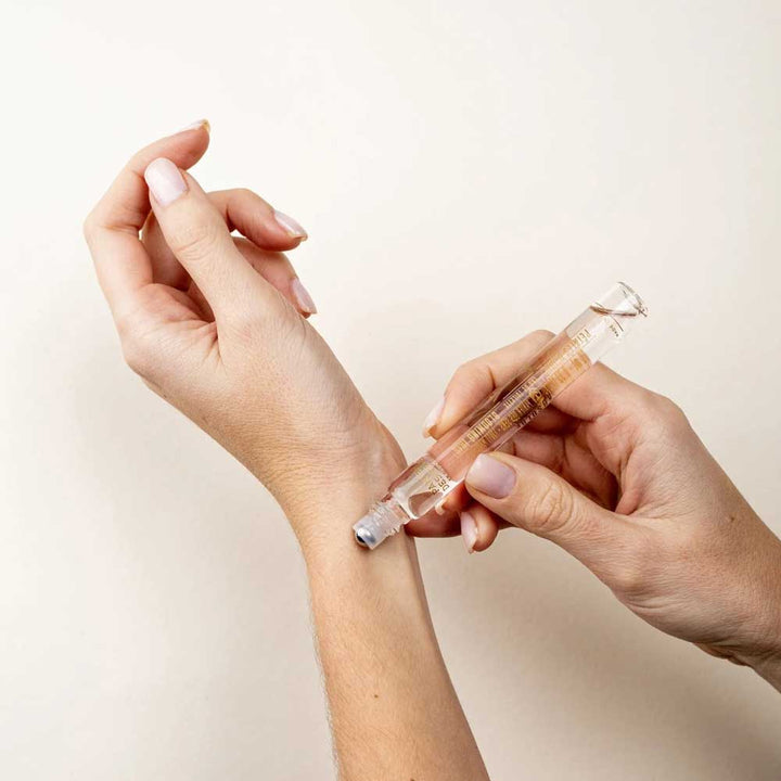 Eine Person trägt Panier des Sens – Eau de Toilette Roll-on Irisblütenblätter 10ml auf die Innenseite ihres Handgelenks auf.