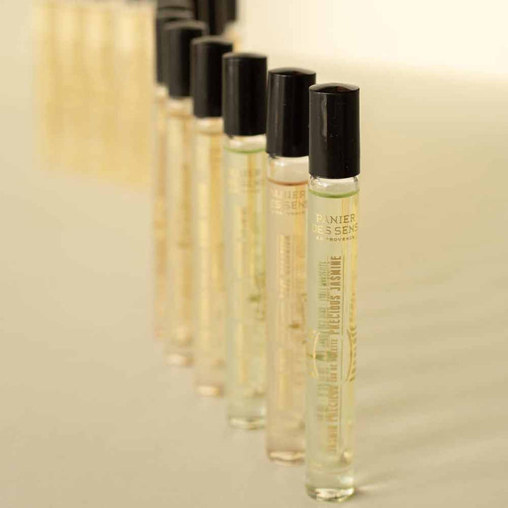 Auf einer weißen Fläche sind mehrere kleine, zylindrische Parfümflakons mit schwarzen Verschlüssen in Reihen angeordnet, jeweils mit der Aufschrift „Panier des Sens – Eau de Toilette Roll-on Jasmin 10 ml“.