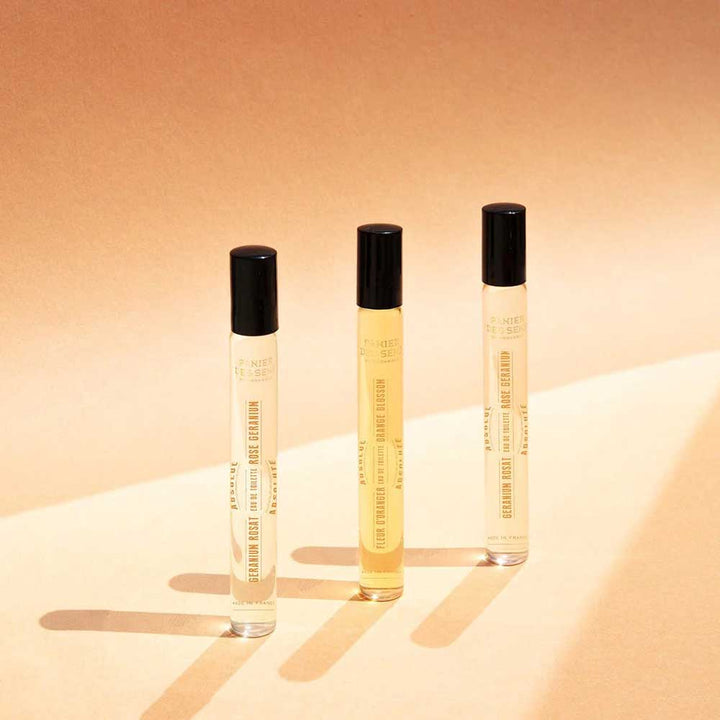 Drei Panier des Sens - Eau de Toilette Roll-on Orangenblüte 10ml Flakons mit schwarzen Verschlusskappen sind in einer Reihe auf beigem Untergrund angeordnet und werfen kleine Schatten.