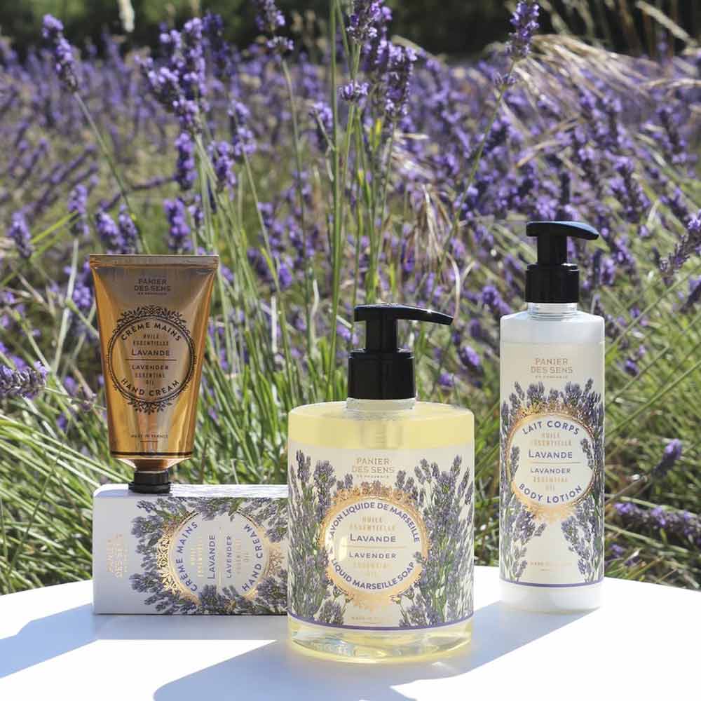 Ein Panier des Sens – Feste Pflanzenseife Lavendel 150 g, präsentiert auf einer weißen Fläche mit einem Lavendelfeld im Hintergrund.