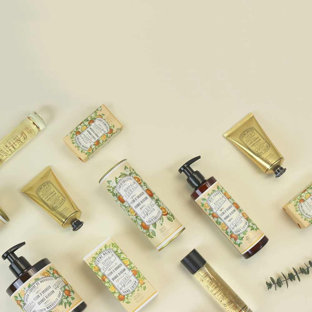 Verschiedene Hautpflegeprodukte und Panier des Sens – Handcreme Orangenblüte, ordentlich angeordnet auf einem pastellfarbenen Hintergrund.