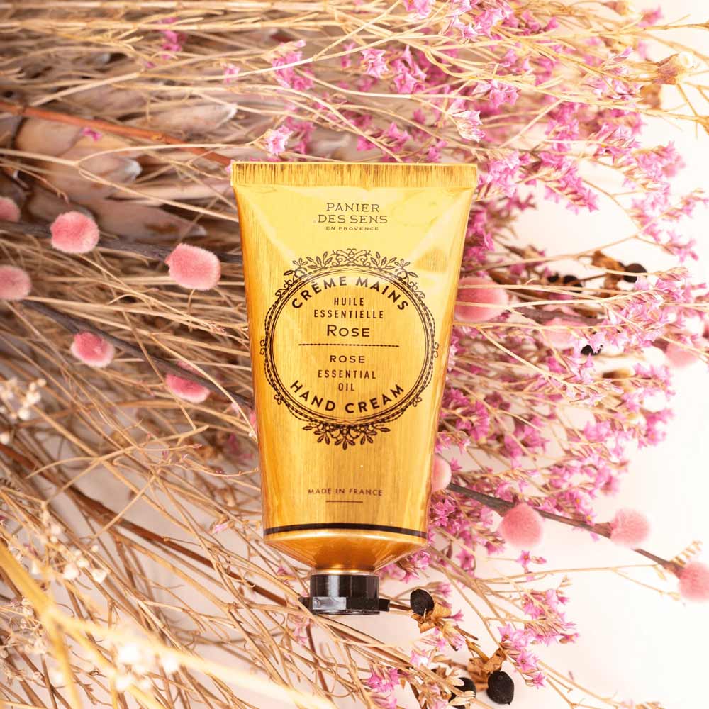 Panier des Sens – Handcreme-Rosentube mit floralen Akzenten auf strukturiertem Hintergrund.