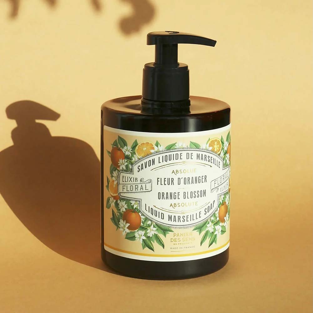 Eine Flasche Panier des Sens – Marseiller Flüssige Handseife Orangenblüte 500 ml, ausgestattet mit einem Pumpspender und einem Etikett mit illustrierten Orangen und weißen Blumen.