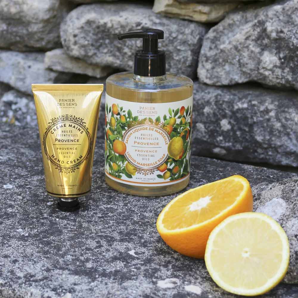 Panier des Sens - Marseiller Flüssige Handseife Provence 500 ml und Flüssigseife mit Verpackung im Zitrus-Design neben frischen Orangenscheiben auf einer Steinoberfläche.