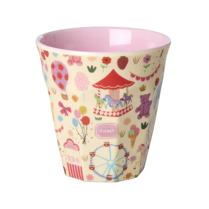 Der Rice Melaminbecher „Fun Fair Medium“ ist in Pastellfarben gehalten, hat eine rosa Innenseite und verspielte Illustrationen von Jahrmarktsymbolen wie einem Karussell, einem Riesenrad, einem Heißluftballon und Eintrittskarten.