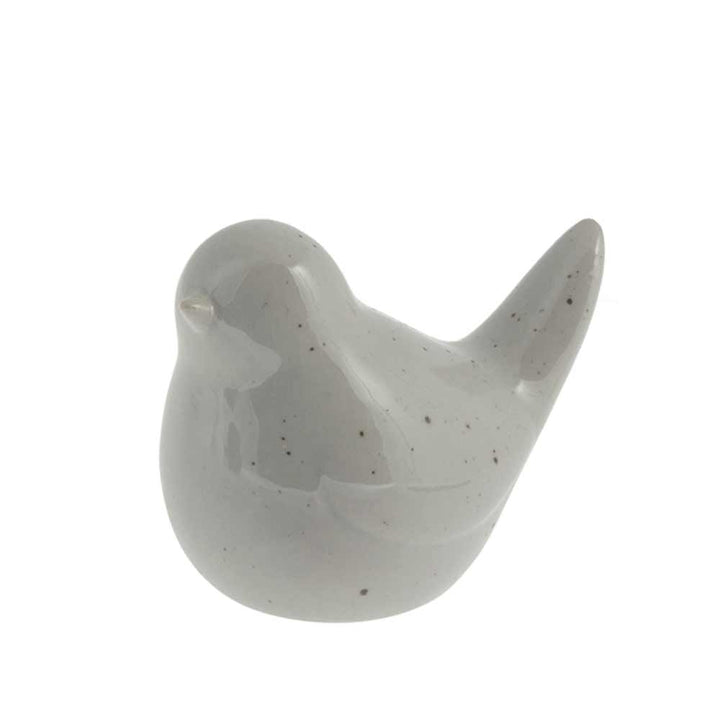 Eine kleine graue Vogelfigur aus Keramik mit glänzender Oberfläche, isoliert auf weißem Hintergrund von Storefactory – Herman Vogel.
