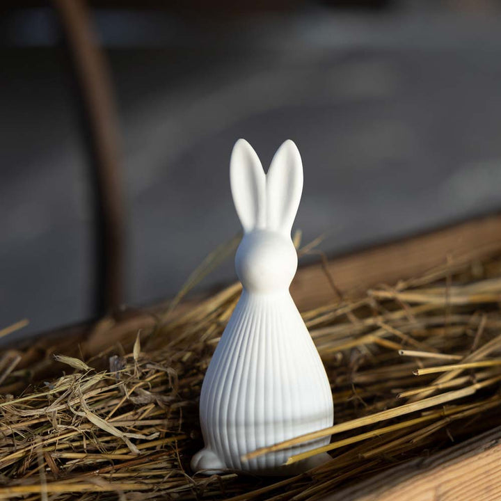 Die Storefactory – Selma Hase ist eine weiße Hasenfigur aus Keramik, die mit dem Rücken zur Figur auf einem Strohbett liegt.