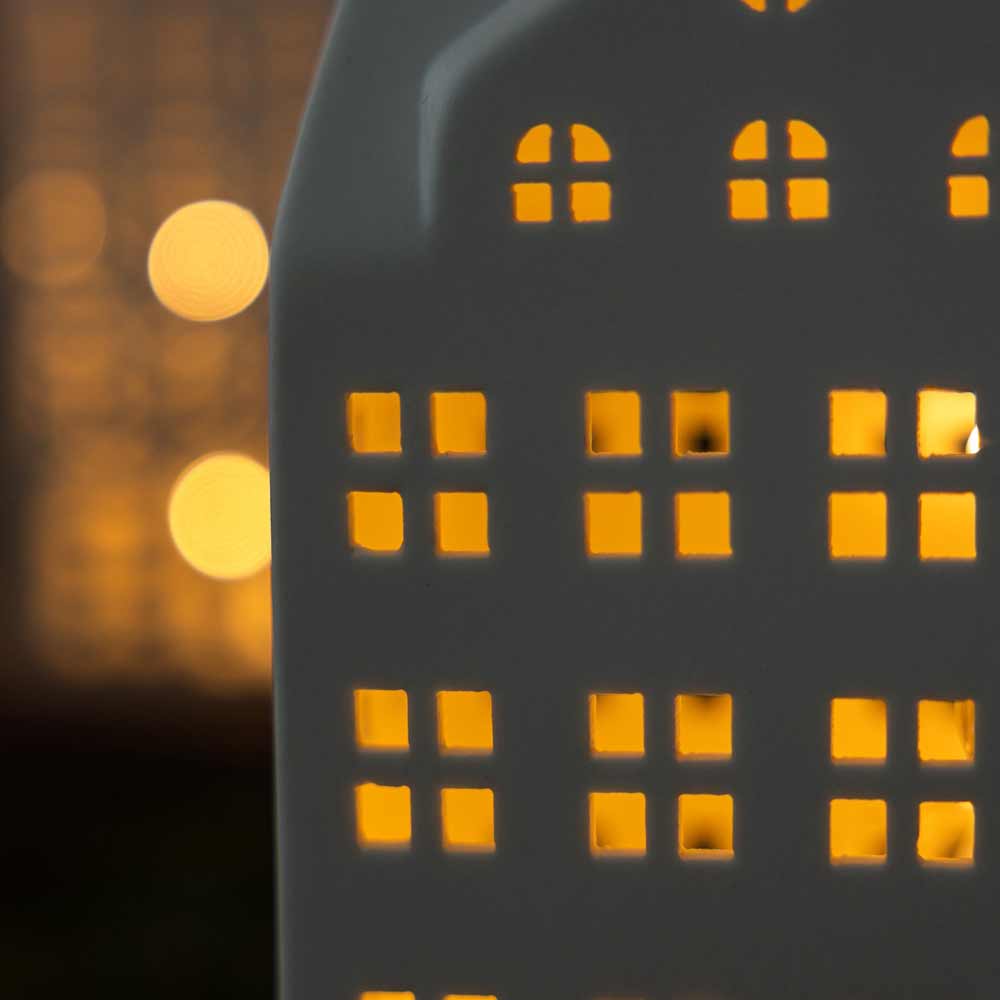 Nahaufnahme der Storefactory – Storstaden Nr. 2 Lichthaus Deko mit beleuchteten Fenstern vor dunklem Hintergrund, mit Bokeh-Lichtern.