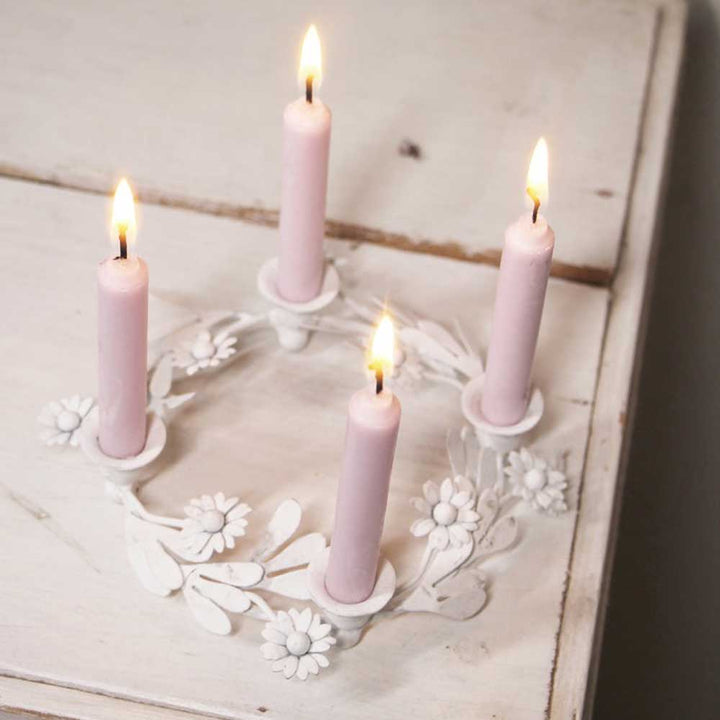 Ein VL Home – Kranz Kerzenhalter mit Blümchen für vier dünne Kerzen mit vier brennenden rosa Kerzen auf einer Holzoberfläche.