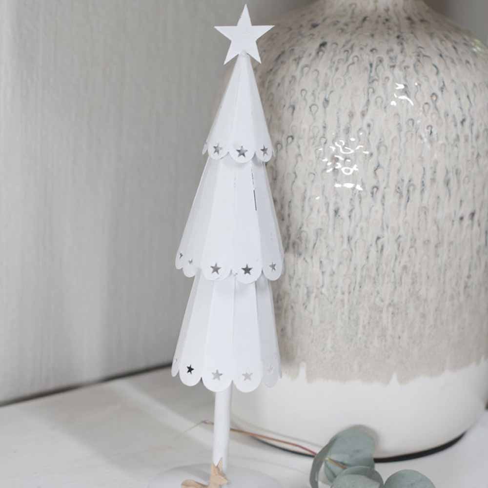 Ein Weihnachtsbaumschmuck von VL Home – Tannenbaum Metall mit Sternen steht auf einem Tisch neben einer strukturierten Keramikvase.