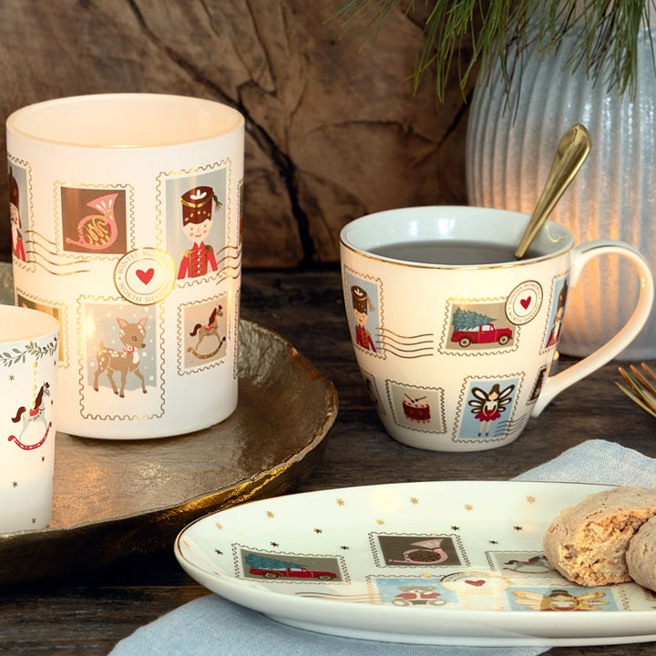 Der GreenGate - Xmas Letter Kalender quadratisch White steht auf einem Holztisch mit Keksen, einer Serviette und einer Pflanze im Hintergrund.