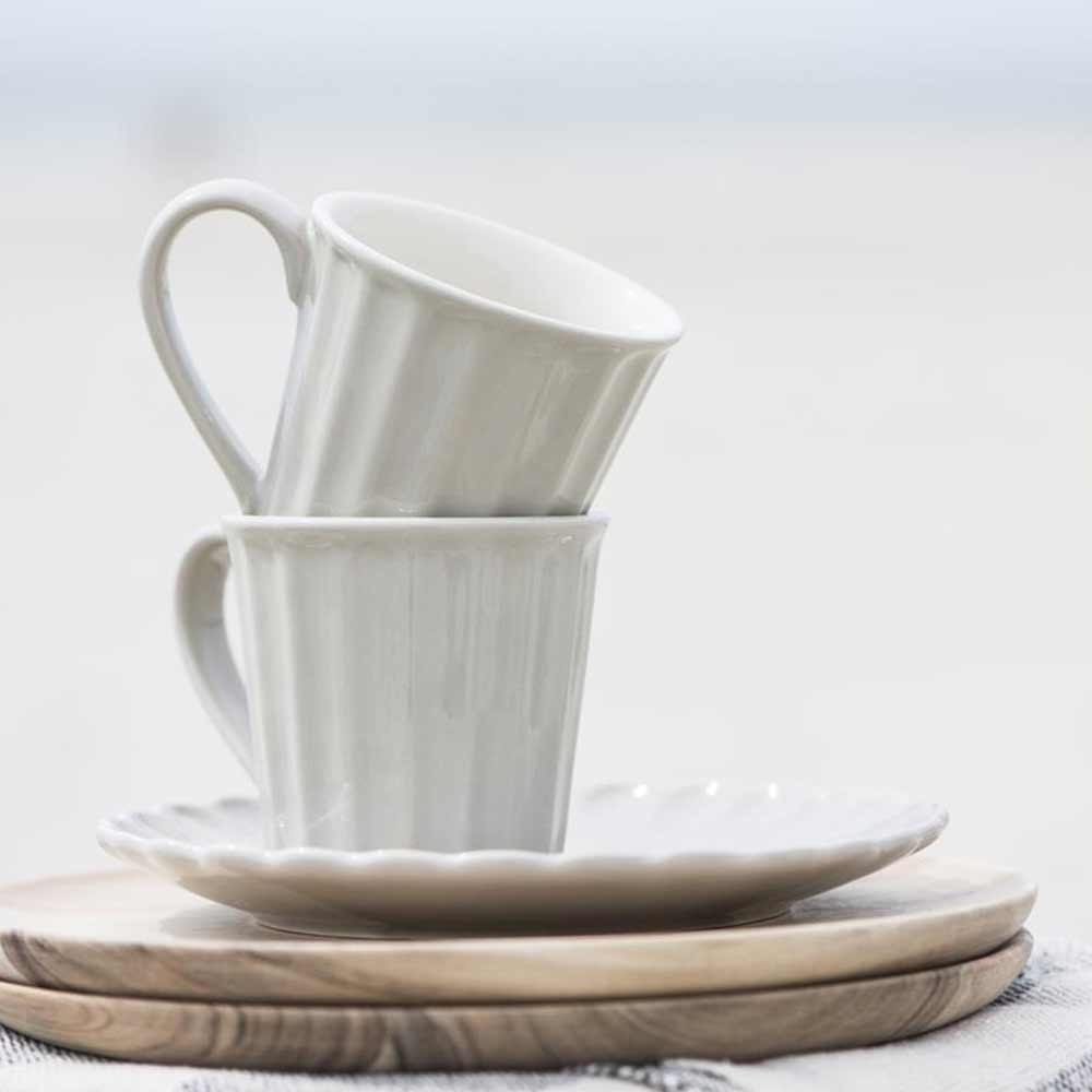 Eine Ib Laursen - Becher Mynte Kaffeetasse und Untertasse auf einem Holzteller.