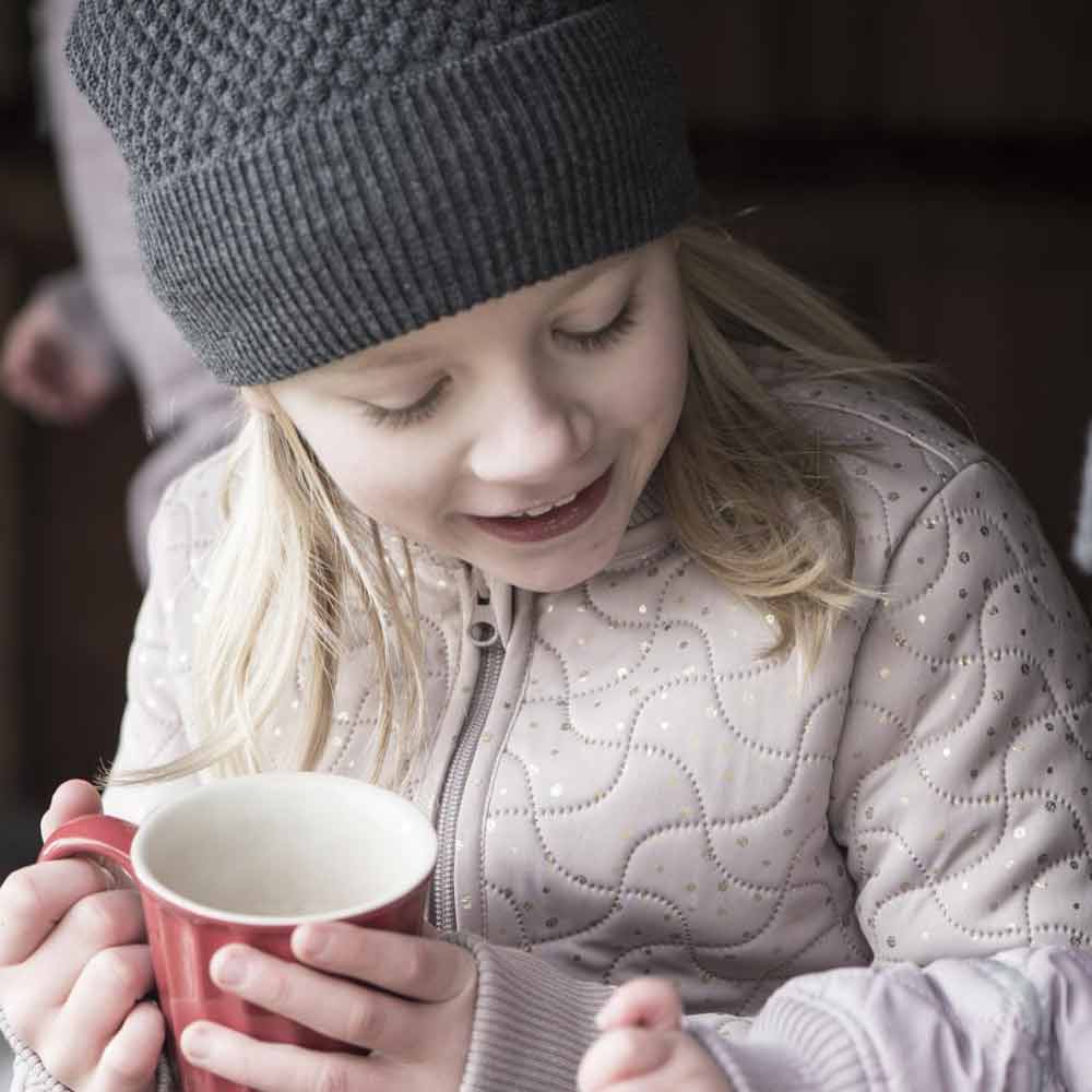 Ein kleines Mädchen hält einen Ib Laursen - Becher Mynte.