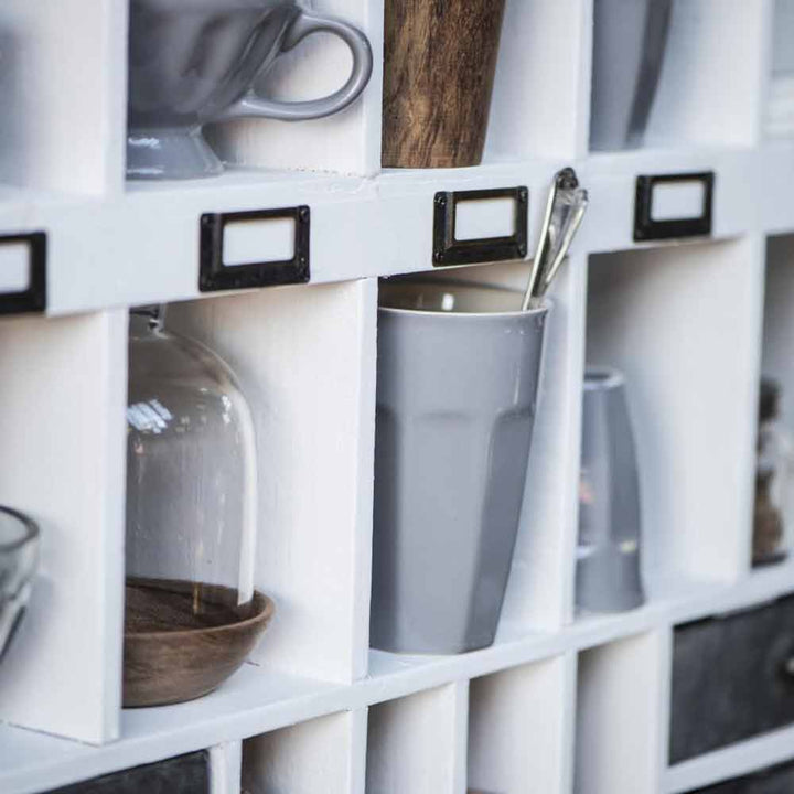 Weißes Regal mit verschiedenen Küchenutensilien und Behältern, darunter Ib Laursen-Café-Latte-Becher „Mynte“ und ein Glas.