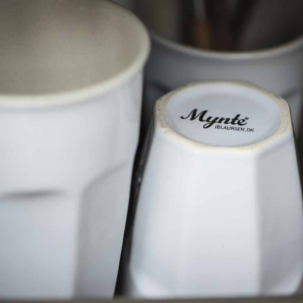 Nahaufnahme von zwei gestapelten Ib Laursen - Cafe Latte Becher Mynte; auf dem Boden des sichtbaren Bechers ist „mynte iblaursen.dk“ in Schwarz aufgedruckt.