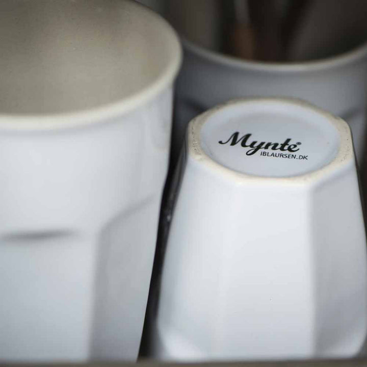 Nahaufnahme von zwei gestapelten Ib Laursen - Cafe Latte Becher Mynte; auf dem Boden des sichtbaren Bechers ist „mynte iblaursen.dk“ in Schwarz aufgedruckt.