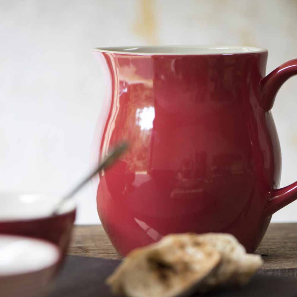 Eine Ib Laursen - Kanne 2,5 Liter Mynte mit glänzender Oberfläche, begleitet von einem verschwommenen Löffel und einem Stück Brot im Vordergrund.