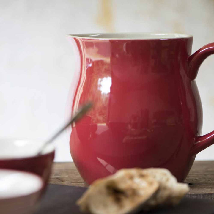 Eine Ib Laursen - Kanne 2,5 Liter Mynte mit glänzender Oberfläche, begleitet von einem verschwommenen Löffel und einem Stück Brot im Vordergrund.