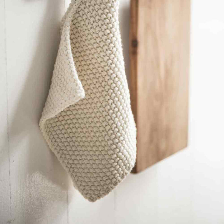 Eine Ib Laursen - Topflappen Mynte hängt an einem Holzgestell vor einer weißen Wand.