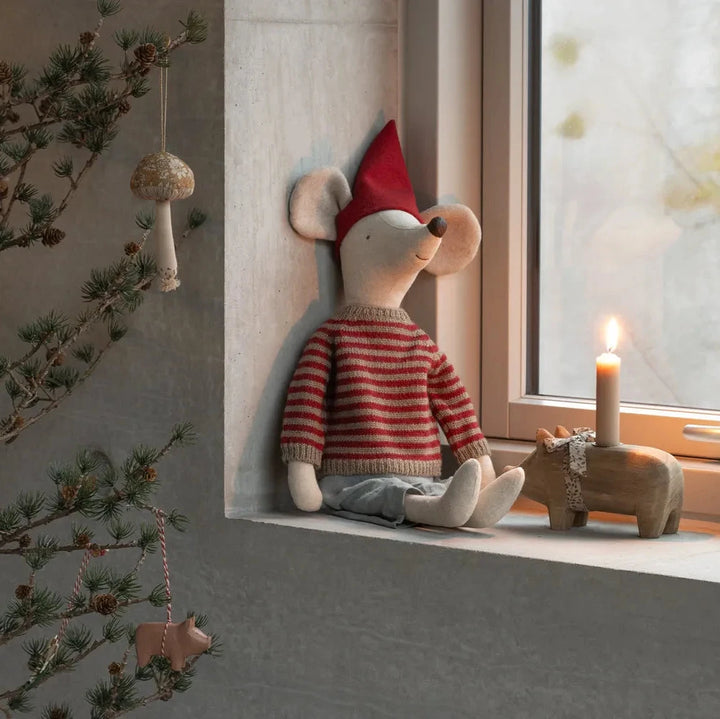 Die Maileg - Weihnachtsmaus Maxi ist eine aufrecht sitzende Plüschmaus, die mit einer roten Mütze, einem gestreiften Pullover und einer blauen Hose ausgestattet ist.