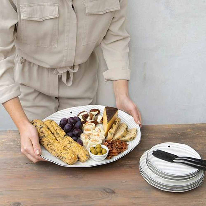 Eine Frau hält eine Bastion Collections - Servierplatte Streifen schwarzer Rand voller Käse und Cracker.