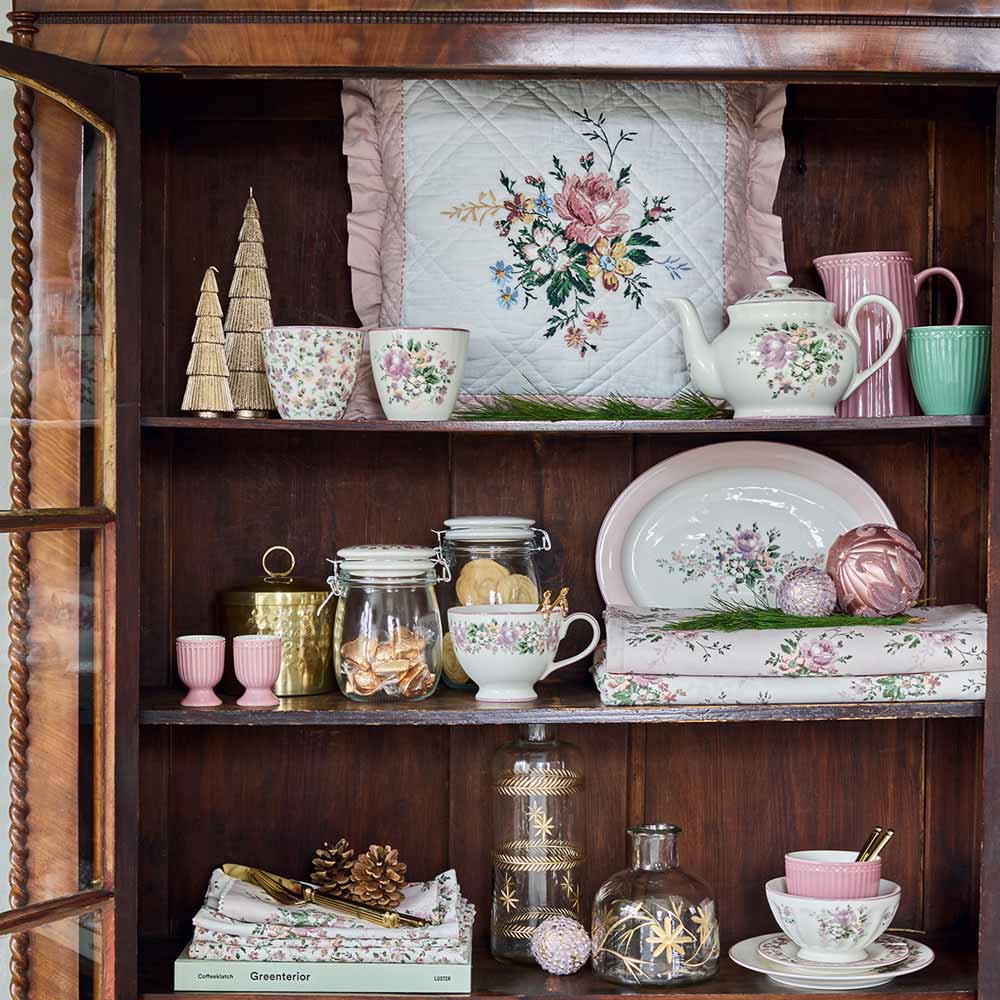 Dunkles Holzregal mit floralen GreenGate-Tellern, Tassen und Vorratsgläsern in Rosa und Grün