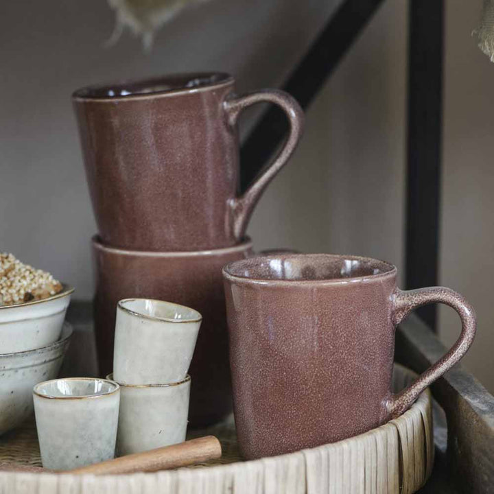 Ein Stapel Ib Laursen - Eierbecher Sand Dunes und kleinere Becher auf einem Holztablett, daneben Körner und ein Holzlöffel.