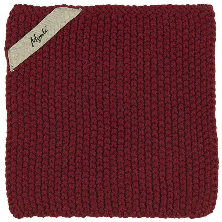 Ein burgunderfarbenes, quadratisches Strickkissen mit einem sichtbaren Markenetikett mit der Aufschrift „Ib Laursen – Topflappen Mynte“ in der oberen linken Ecke.