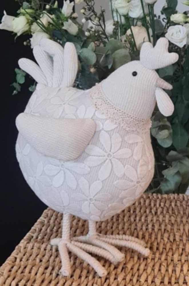 La Galleria - Huhn mit Blumenspitze kurze Beine cremeweiß vor einem floralen Hintergrund auf einer gewebten Oberfläche.