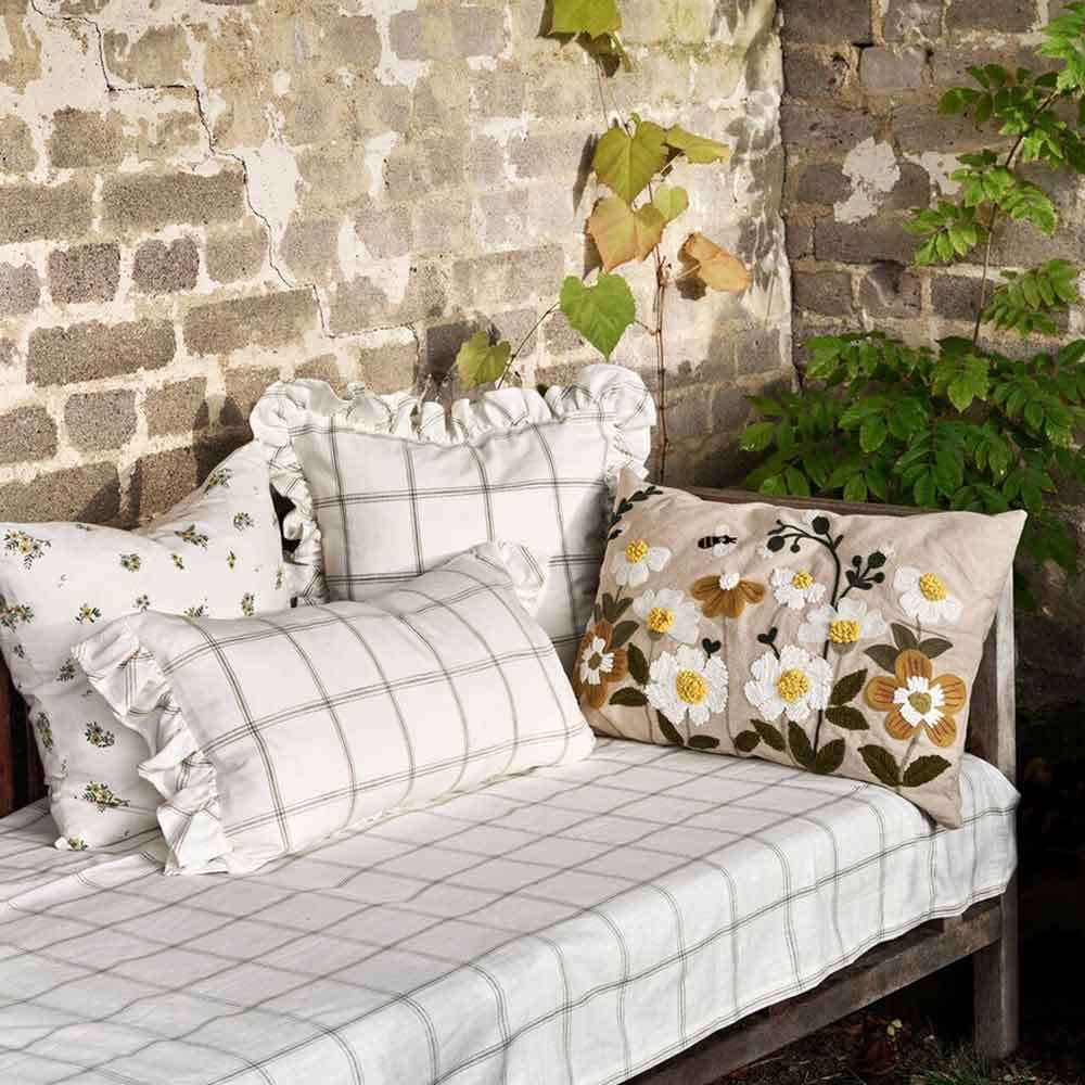 Outdoor-Bank mit Strömshaga – Kissenbezug Alma 45 x 45 cm vor einer alten Backsteinmauer mit Efeu.